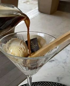 ice cream being poured into a martini glass filled with ice cream and caramel sauce