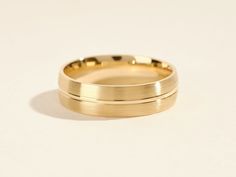 two gold wedding bands sitting next to each other on a white surface with no background