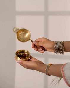 two women are holding small bowls and spoons with tea in them, one is empty