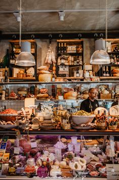 a man standing behind a counter filled with lots of food