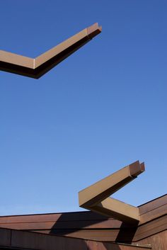 a kite flying in the air over a building with wooden roofing and metal beams