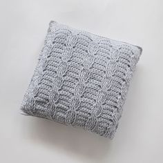 a gray knitted pillow sitting on top of a white table