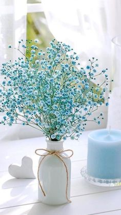 a vase with blue flowers and a candle on a table