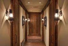 an empty hallway with wood paneling and two lights on either side of the door