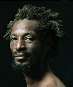 a man with dreadlocks on his face and chest is looking at the camera