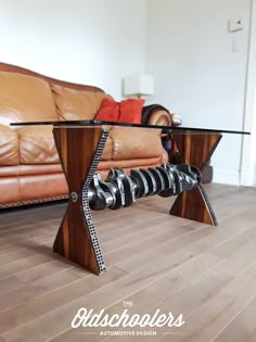 a glass table sitting on top of a wooden floor next to a brown leather couch