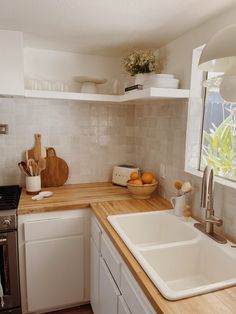 a kitchen with white cabinets and wooden counter tops