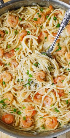 pasta with shrimp and parmesan cheese in a skillet on a wooden table