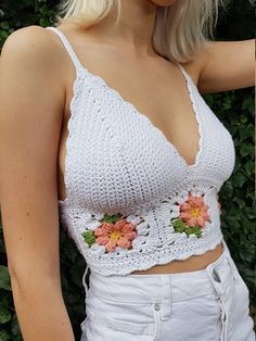 a woman with blonde hair wearing a white crochet crop top and flowered shorts