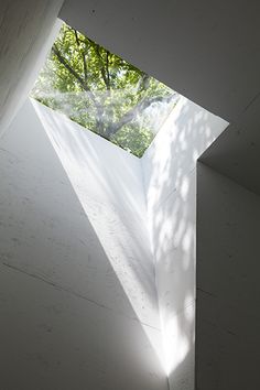 an open window in the side of a building with sunlight coming through it and trees outside