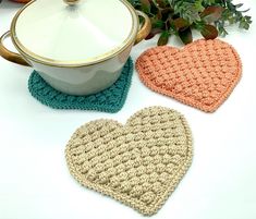 three crocheted heart shaped coasters next to a pot holder