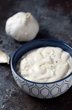 a bowl filled with white sauce next to garlic