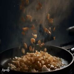 onions being cooked in a frying pan on top of the stove with oil pouring over them