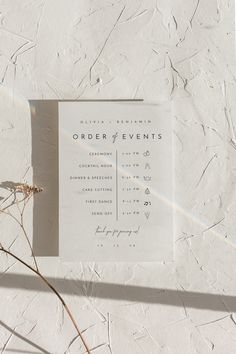 an order of events card sitting on top of a piece of paper next to a plant