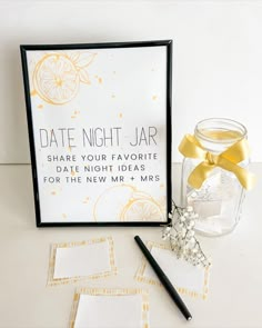 a glass jar with a yellow ribbon next to some cards and a pen on a table