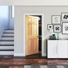 an open door in a white room with pictures on the wall and wooden flooring