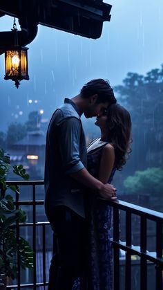 a man and woman standing next to each other on top of a balcony in the rain