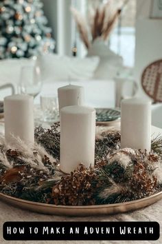 white candles on a tray with greenery and pine cones