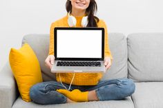 a woman is sitting on the couch with her laptop and headphones in front of her