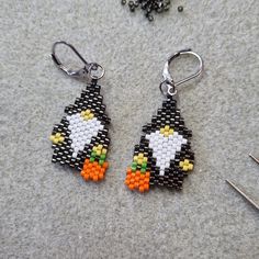 a pair of beaded penguin earrings sitting on top of a table next to scissors