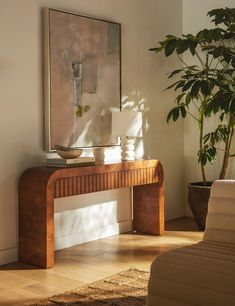 a living room with a plant and a painting on the wall