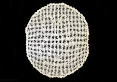 a white doily is shown on a black tablecloth with an oval design in the center