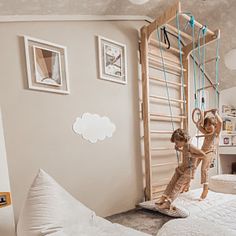 two children playing on a bed in a room with white walls and pictures above the bed