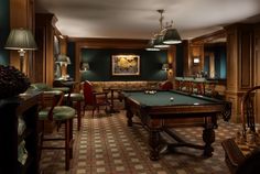 a billiard table in a room with chairs and lamps on either side of the pool table