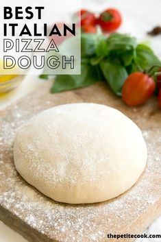 a pizza dough sitting on top of a wooden cutting board next to tomatoes and basil