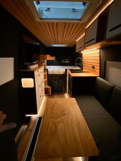 an interior view of a camper with wood flooring and black couches in the foreground