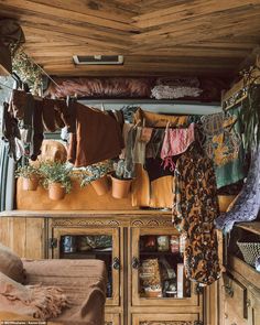 the inside of a van with clothes hanging from it's racks and potted plants