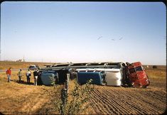 two men standing next to an old truck in the middle of a field