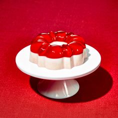 a cake on a white plate with red icing sitting on a red tablecloth