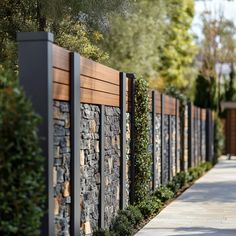 a stone wall and wooden fence in the middle of a sidewalk with trees on both sides