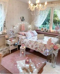 a bedroom decorated in pink and white with flowers on the bed, chandelier