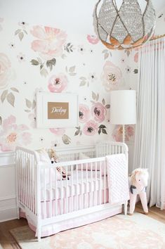 a baby's room with floral wallpaper and pink crib in the corner