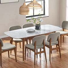 a dining room table with chairs and a vase on the top, in front of a window