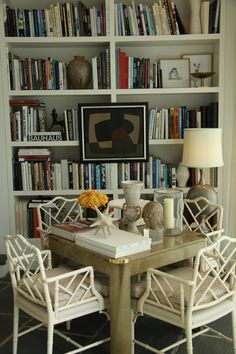 a dining room table and chairs with bookshelves in the background