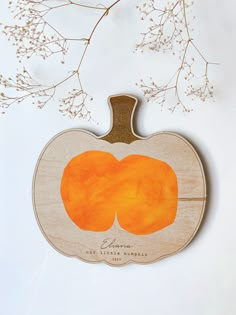 a wooden cutout of two pumpkins sitting on top of a white table next to branches