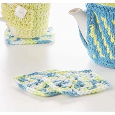 crocheted tea pot and coasters on a white table with blue and yellow accents