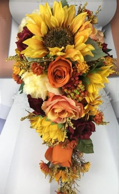 a bridal bouquet with sunflowers, roses and other flowers on it's side