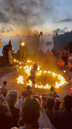 people sitting around a fire pit in the middle of a crowd at sunset or sunrise