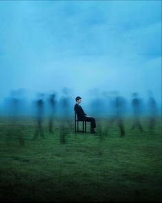 a man sitting on top of a chair in a field