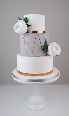 a three tiered cake with white flowers and gold trimmings on a plate