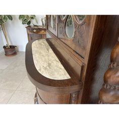 a wooden bench with marble top and mirror on the back wall next to a potted plant