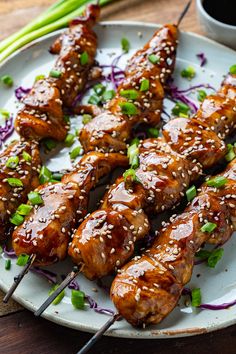 chicken skewers with sesame seeds and green onions on a plate