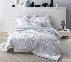 a bed with white sheets and pillows in a room