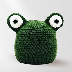 a crocheted green frog hat with big eyes and two large white eyeballs