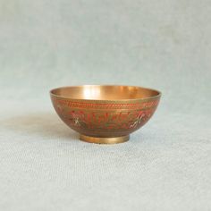 a gold colored bowl sitting on top of a white cloth covered table next to a wall