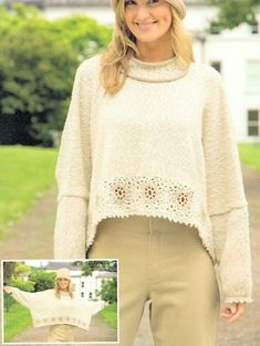 a woman wearing a white sweater and tan pants standing in front of a green field